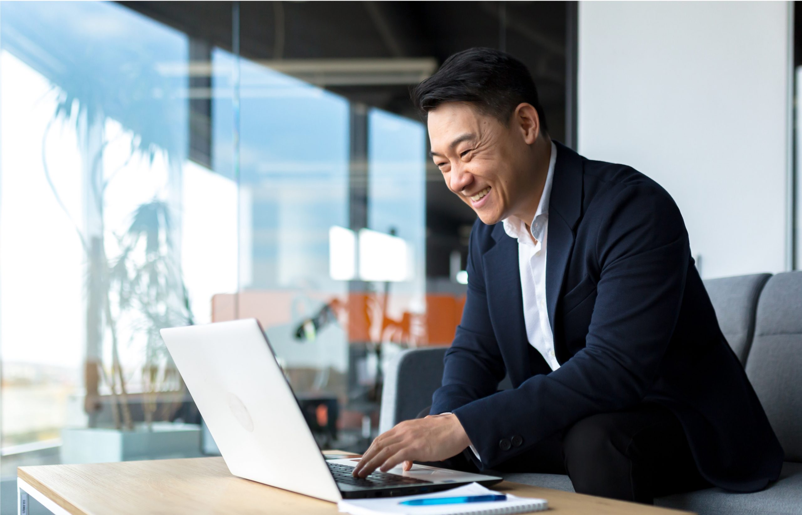 Senior Asian business man working on laptop online, smiling and rejoicing, happy boss business owner working in office