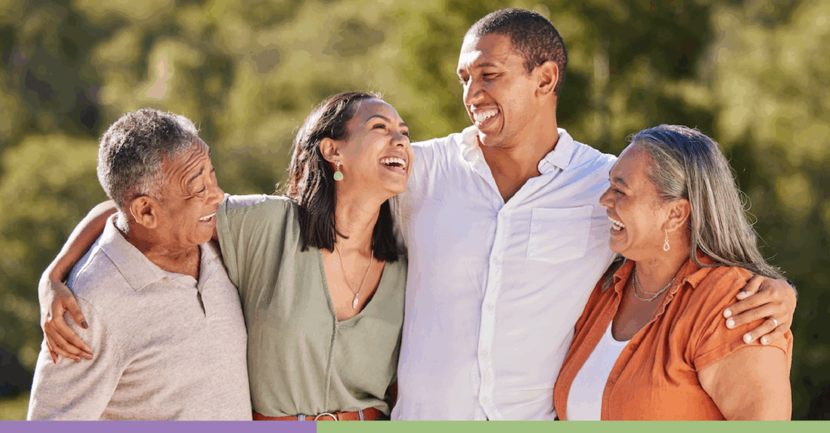 A multi-generational family, facing forward and laughing in an outdoors space